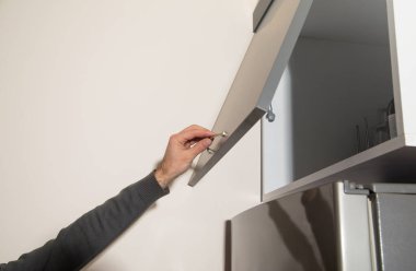 Erkek el mutfak dolabının kapısını açıyor..