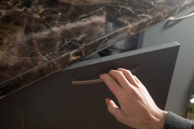 Erkek el mutfak dolabının kapısını açıyor..