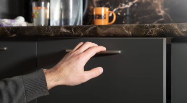 Erkek el mutfak dolabının kapısını açıyor..