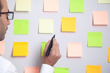 İşadamı ofiste yapışkan notlarla çalışıyor..