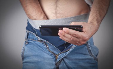 Akıllı telefondan yetişkin içeriğini izleyen adam.