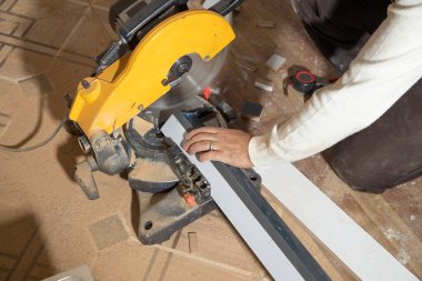 Mobilyanın bir kısmını kesme makinesiyle kesen işçiler.