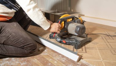 Mobilyanın bir kısmını kesme makinesiyle kesen işçiler.