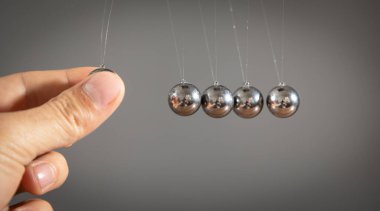 Erkek el Newton 'un beşik toplarını gösteriyor.