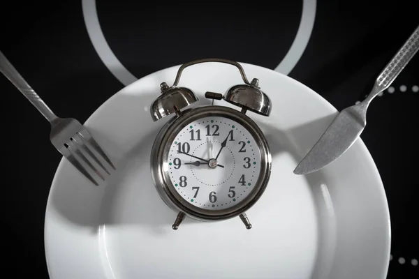Plate with a alarm clock fork and knife.