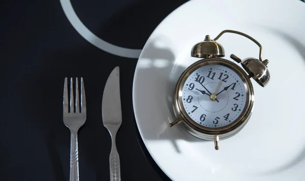 Plate with a alarm clock fork and knife.