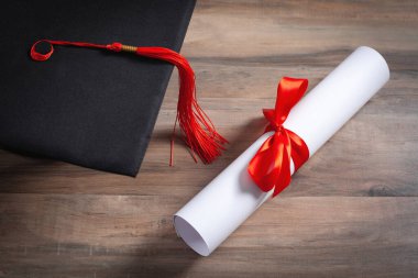 Tahta arka planda mezuniyet şapkası ve diploması var..