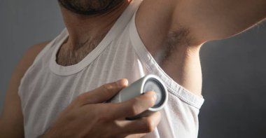 Genç adam koltuk altına deodorant sıkıyor..