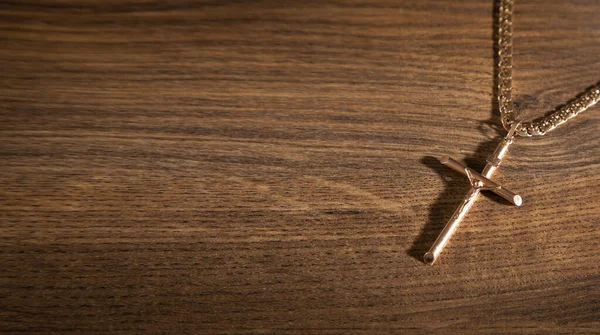 stock image Golden cross necklace on wooden background.