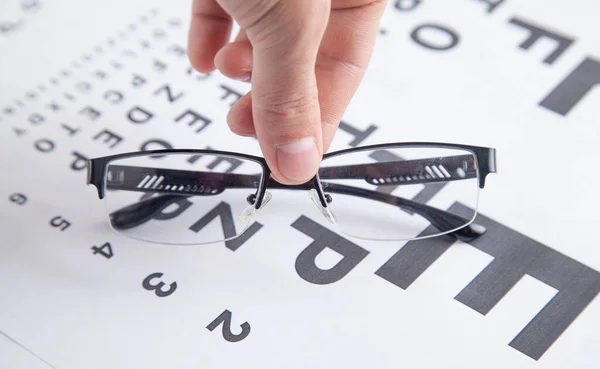眼鏡をかけた男性の手 目の検査表 医療眼診断 — ストック写真