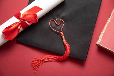 Bordeaux arka planında mezuniyet şapkası ve diploması..