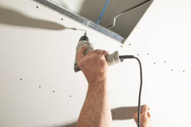 Matkap tornavidalı bir işçi vidayı alçıpana çeviriyor..