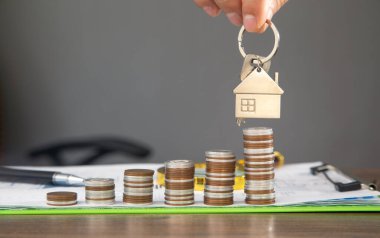 Erkek el bozuk para yığınının üzerinde evin anahtarlarını gösteriyor..