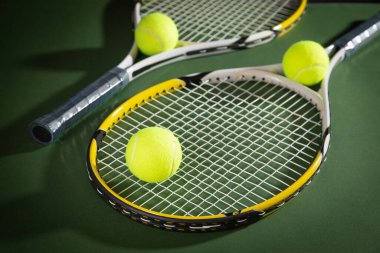 Yeşil arka planda tenis topu ve raketler.