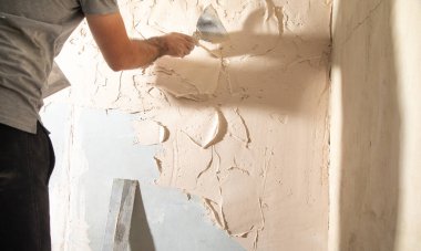 Adam duvara macun yapıştırıyor. Ev yenileniyor. 