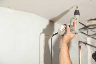 Matkap tornavidalı bir işçi vidayı alçıpana çeviriyor..