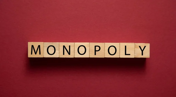 stock image Word Monopoly on wooden cubes on the bordeaux background.