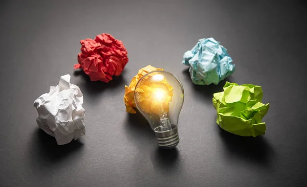 Colorful paper balls and light bulb on the black background.