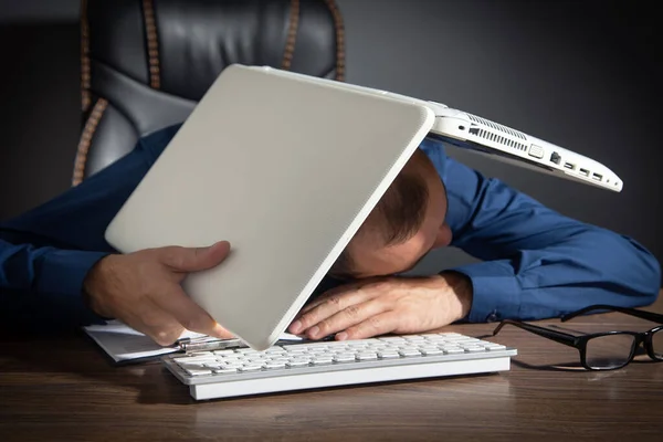 带着笔记本电脑睡在桌子上的疲倦的工人 — 图库照片