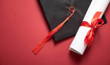 Bordeaux arka planında mezuniyet şapkası ve diploması..