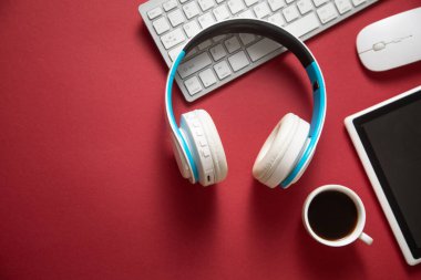 Bordo arka planında beyaz kablosuz kulaklık, kahve ve diğer nesneler var..