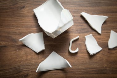 Ahşap arka planda beyaz kırık bardak..