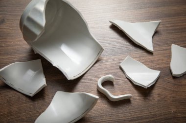 Ahşap arka planda beyaz kırık bardak..