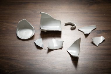 Ahşap arka planda beyaz kırık bardak..