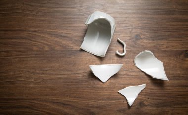 Ahşap arka planda beyaz kırık bardak..