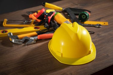 Ahşap arka planda miğferi olan çalışma araçları.