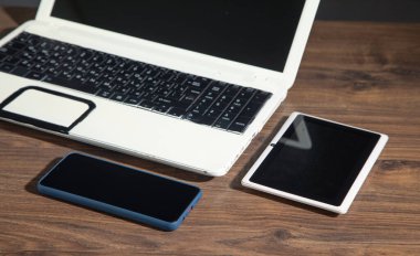 Ahşap masada akıllı telefon, tablet, dizüstü bilgisayar.