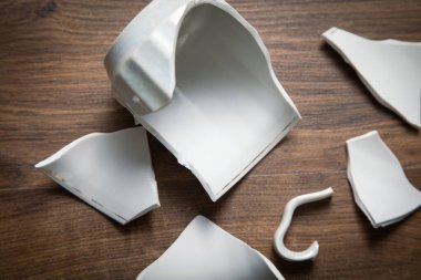 Ahşap arka planda beyaz kırık bardak..