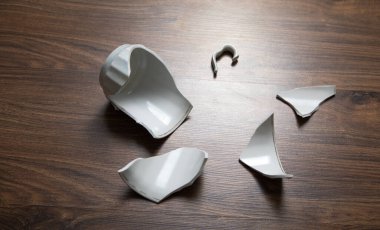 Ahşap arka planda beyaz kırık bardak..