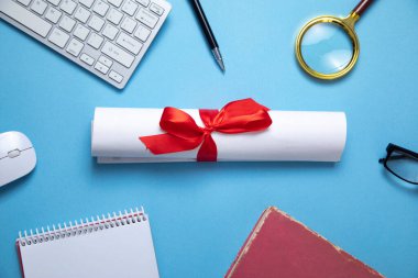 Mavi arkaplanda diploma ve iş objeleri.