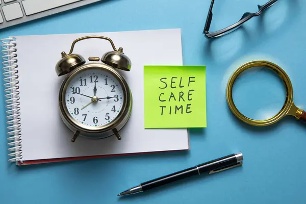 stock image Self care time on sticky note with a clock and business objects.