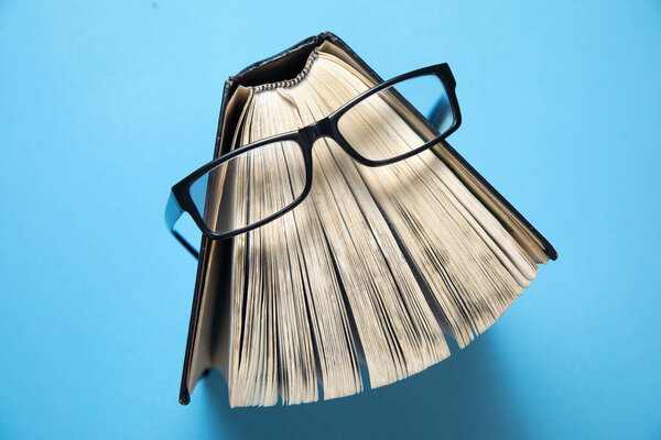 Очки и книги на синем фоне.