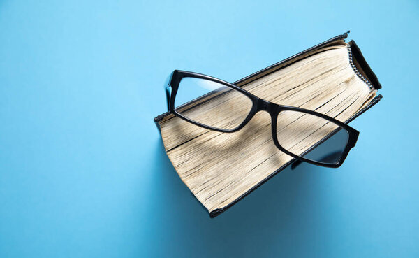 Очки и книги на синем фоне.