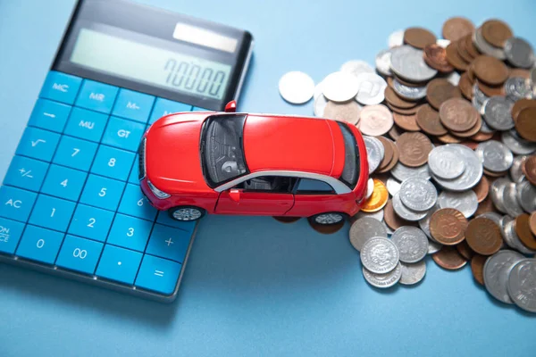 stock image Red toy car, calculator and coins on the blue background.