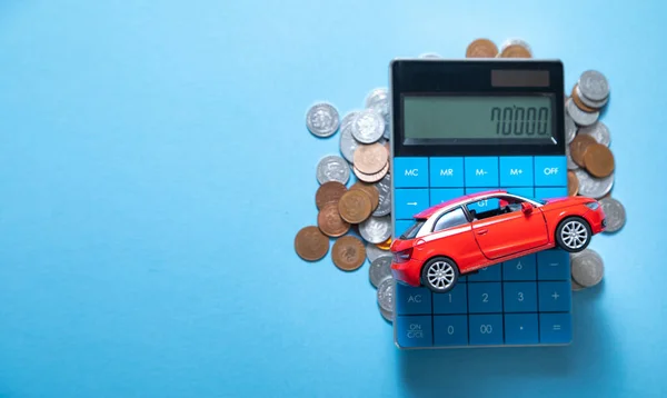 蓝色背景上的红色玩具车 计算器和硬币 — 图库照片