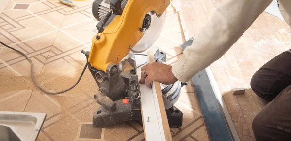 Mobilyanın bir kısmını kesme makinesiyle kesen işçiler.