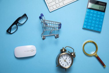 Alarm saati, mavi arka planda alışveriş arabası..