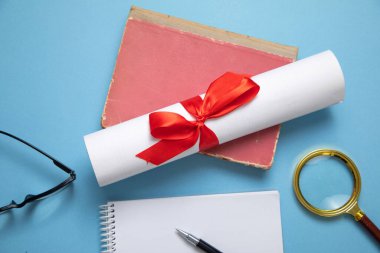 Mavi arkaplanda diploma ve iş objeleri.