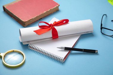 Mavi arkaplanda diploma ve iş objeleri.