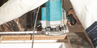 Elektrikli testereyle mutfak tezgahını kesen işçiler.