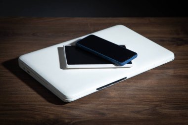 Ahşap masada akıllı telefon, tablet, dizüstü bilgisayar.