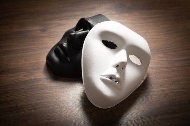 Ahşap masada siyah ve beyaz bir maske..