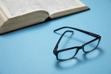 Mavi arka planda gözlük ve kitap.