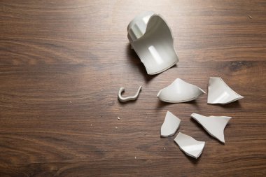 Ahşap arka planda beyaz kırık bardak..