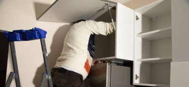 Yeni mutfak mobilyalarının işçiler montajı.