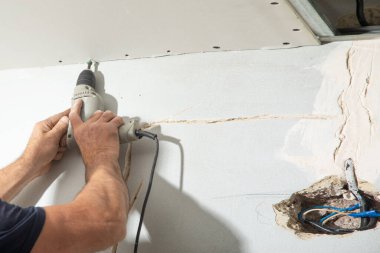 Matkap tornavidalı bir işçi vidayı alçıpana çeviriyor..